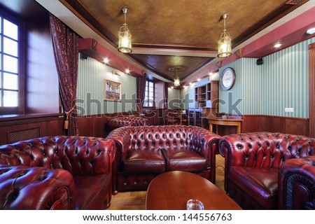 Luxurious english cigar room with leather armchairs and wooden round table.
