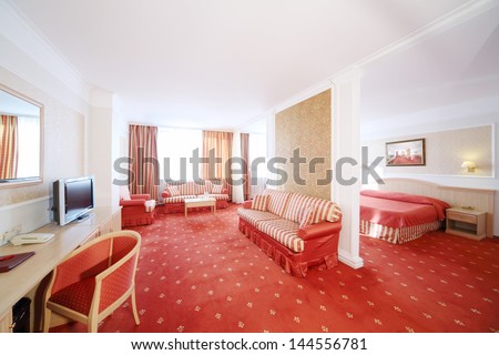 Beautiful living room with soft striped sofas and bedroom with red carpet flooring.