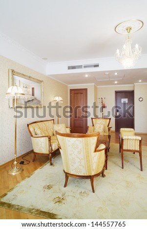 Beautiful living room with luxurious armchairs, sofa, table in classic style.