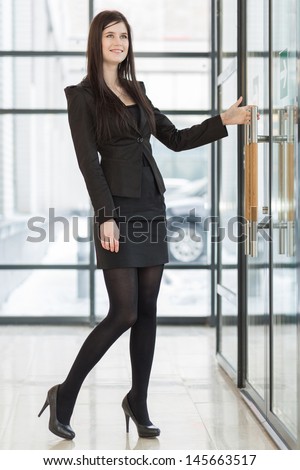 Smiling business woman pulling the door handle