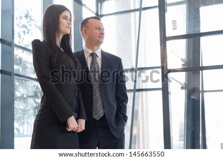 Man and woman stand near the glass windows