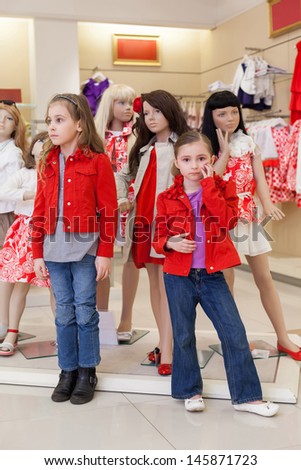 MOSCOW - MAR 18: Anya 7 years old and Jeanette 6 years old trying on clothes together with mannequins in the store children clothes Jakimanka on March 18, 2012 in Moscow, Russia.