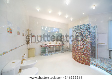Light and clean bathroom with toilet, bidet, shower cabin with blue tiles.