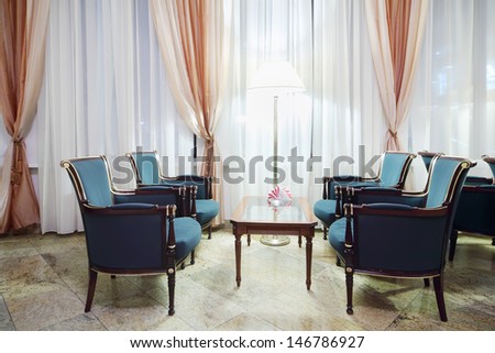 Cozy room with table and green chairs and large windows with curtains.