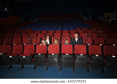 Parents with three children watching a movie in empty cinema hall