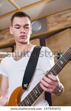 Young bass player with tattoo standing with his guitar