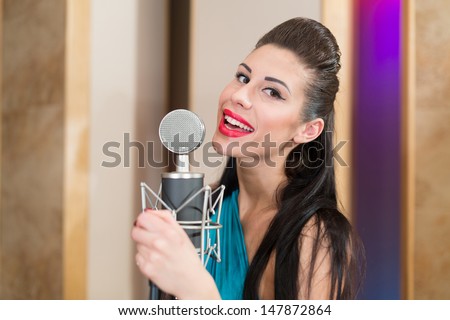 Girl with beautiful eyes and red lips in room with microphone in Recording Studio