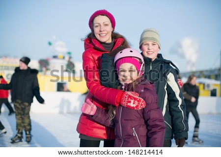 A mother with two children standing on the outdoor skating rink in winter