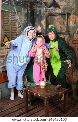 Father, mother and little daughter in colorful costumes of dragons attack in very old room.