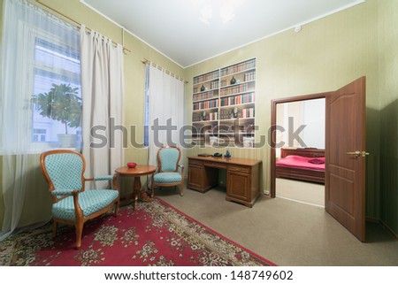 Interior room sitting area with two chairs and an open door leading to the bedroom
