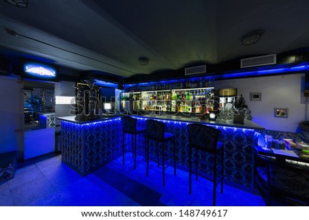 The Bar Counter In Cafe With Three Chairs Illuminated With Blue Light