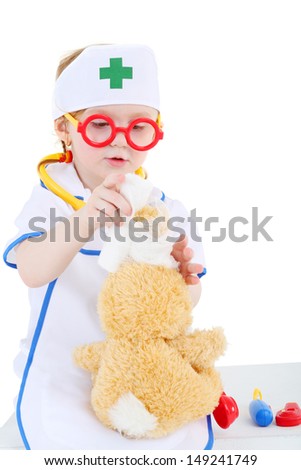 Little girl dressed as nurse and in glasses bandages head to toy rabbit isolated on white background.