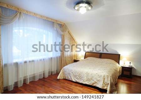 Bedroom with beautiful bed with bedside tables, big window in classic style.