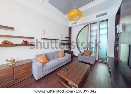 Contemporary Room With A Sofa, An Armchair And A Wooden Table In The Center