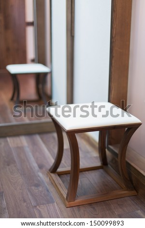 Low square stool with a padded seat in a modern interior decorated in wood