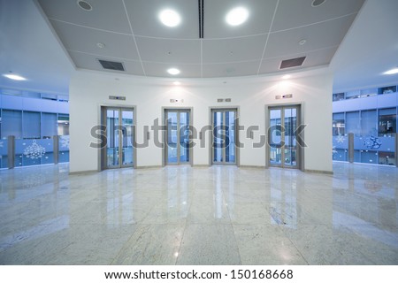 Four Transparent Elevator Door In The Business Building With Marble Floor