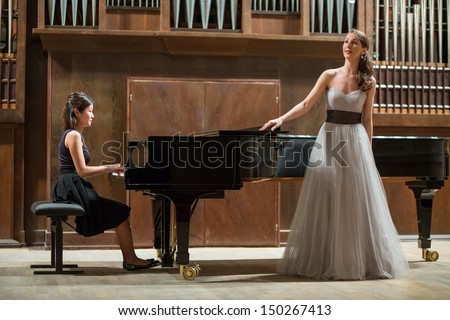Woman Pianist Plays The Piano And Beautiful Singer Stands Next