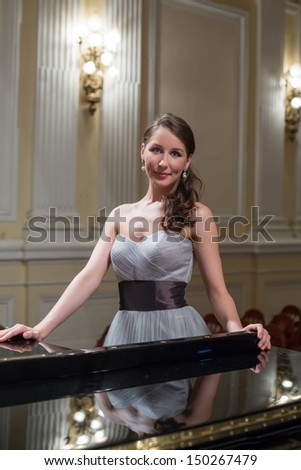 Beautiful opera singer in the concert hall next to the piano