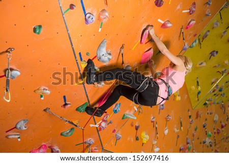 The girl climbs the steep wall on the climbing gym