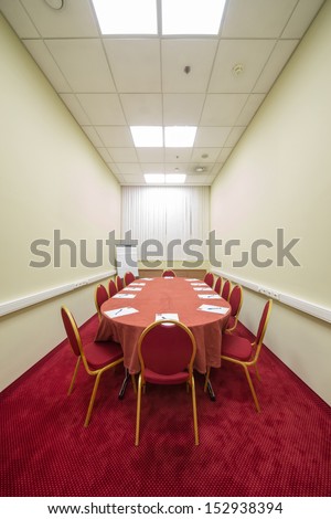 Chairs and table in empty conference room with a red carpet on the floor