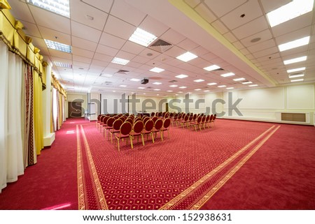 Screen and chairs in elegant empty conference hall with a red carpet on the floor