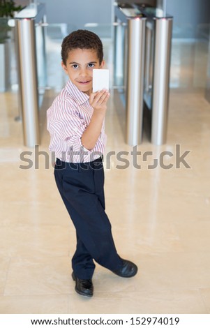 Mulatto boy in a shirt with a card in his hand near the entrance to the business center