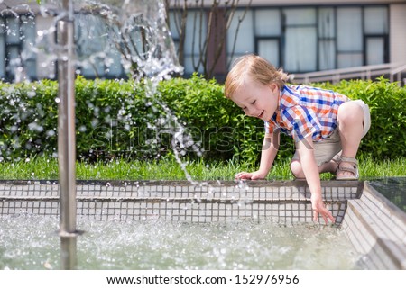 Little boy draw water from the fountain in the park