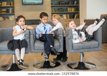 Four children in business clothes having fun in a business center