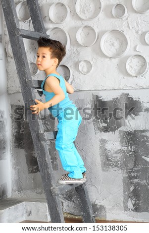 A little boy stands on a wooden ladder