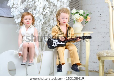 A little girl in white dress and pop musician with guitar sit on letters love