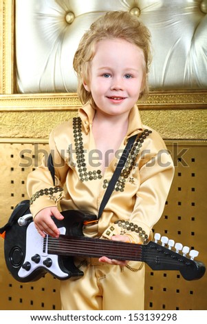 A little boy in pop retro suit with guitar