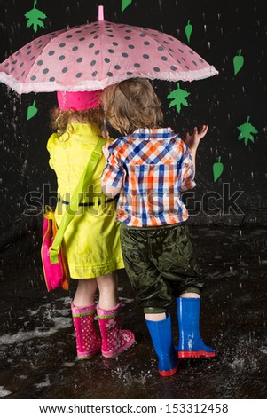 Little girl and boy hiding under a pink umbrella, view from back