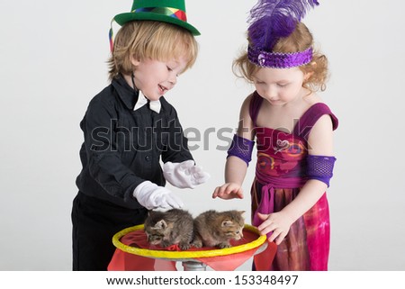 Two children in costumes magicians and two kittens on a round table