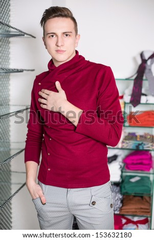 The man in gray pants and a red sweater in a clothing store
