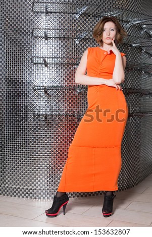 The girl in the orange dress and black shoes with red line in the studio
