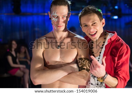 The guy in the red shirt and a guy with a naked torso and scary pupils at a party
