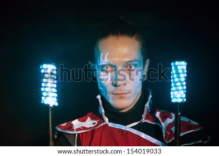 Man with tattoo on face and terrible pupils in samurai garb with glow sticks