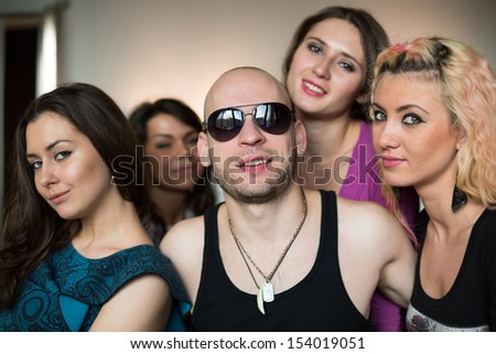 Bald man with an amulet in the form of fang and four beautiful girls