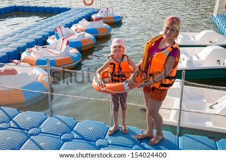 Mother and daughter on the dock with round inflatable boats with electric motor