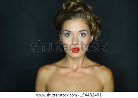 Portrait of a frightened woman with eyes wide open on a dark background