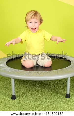 Little boy sitting on his lap on a small trampoline, his arms outstretched