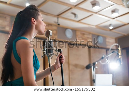 MOSCOW - DEC 25: Girl in cyan dress with microphone in Recording Studio Nautilus on December 25, 2012 in Moscow, Russia.