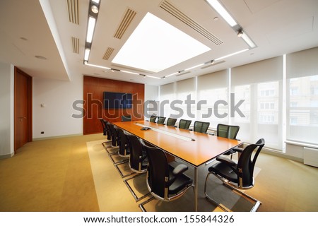 Long table, black armchairs in light room for business meetings.