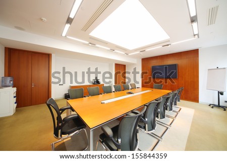 Long wooden table, black armchairs in light room for business meetings.