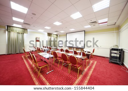 Tables with bottles with water and red chairs in room for business meetings.
