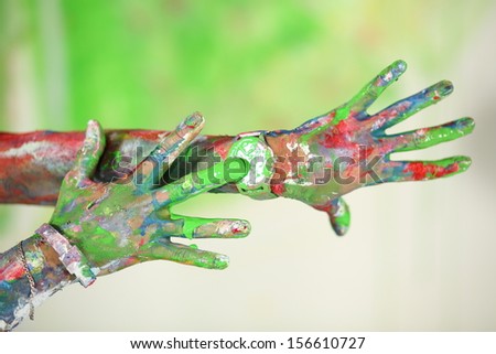 Two hands all in the paint with the wristwatches in green paint
