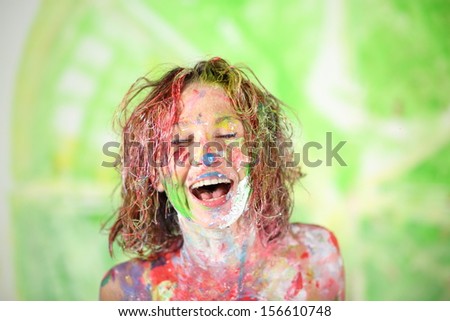 Face laughing girl covered in paint with closed eyes