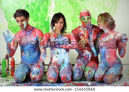 Four people sitting on the floor in studio with whole body in the paint and make hand gestures