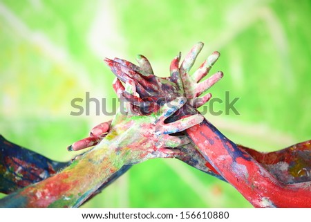Interlacing female and male hands in the paint of different colors make a figure