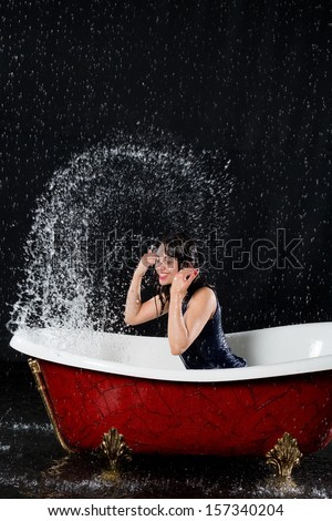Wet girl have fun in the bathtub under the spray of water
